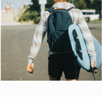 Traveler with surfboard and Hudson Sutler backpack